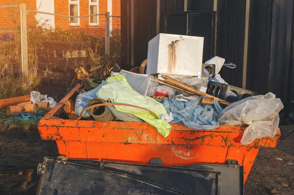 Full,orange,construction,debris,dumpster,outside,brick,building